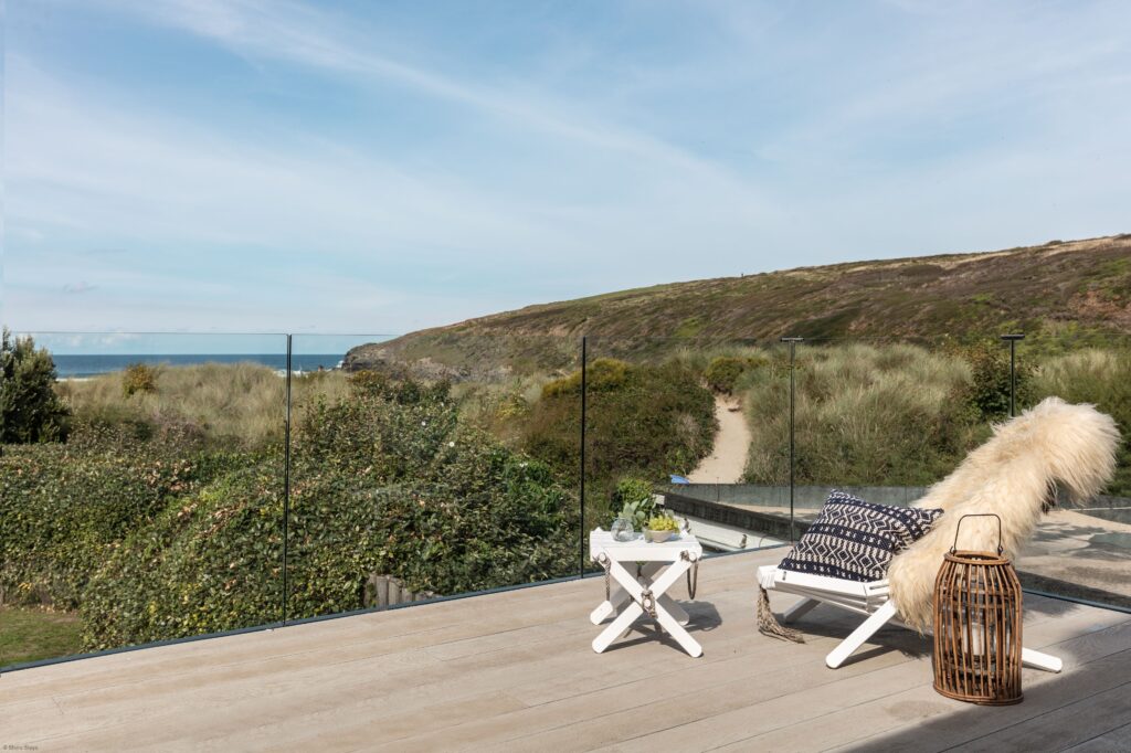 Rooftop deck with a  lounge chair and cushion overlooking the sea.