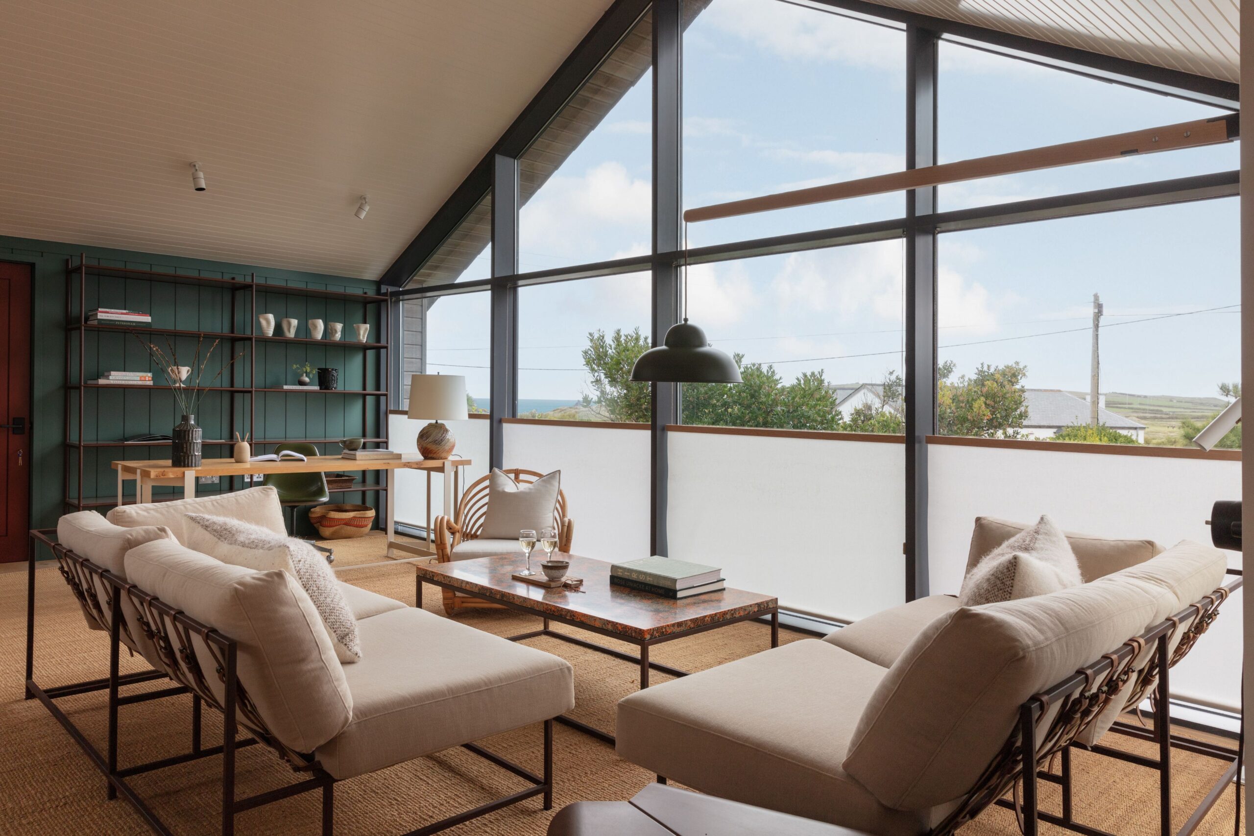 A modern living room with large windows showcasing a coastal view.