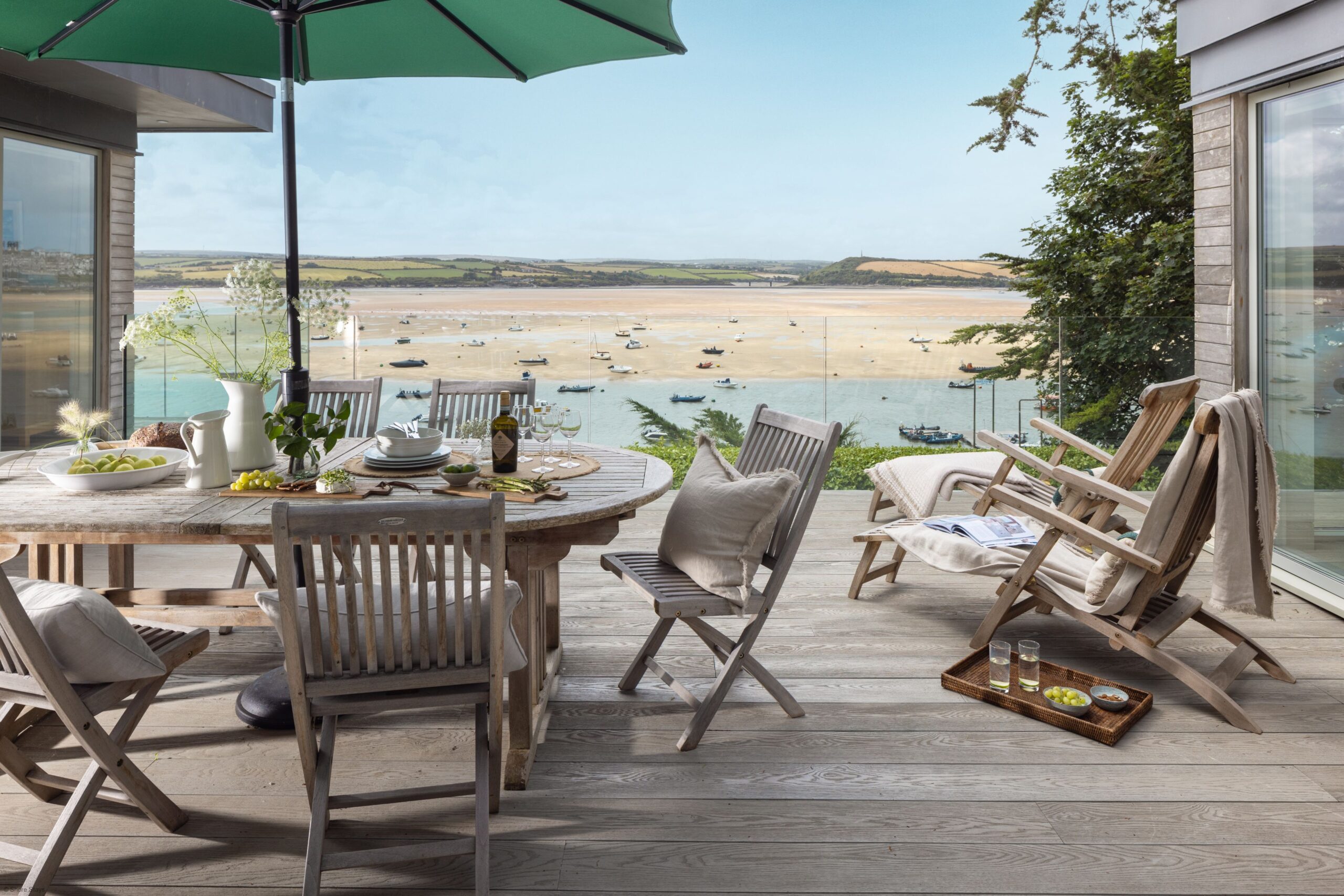 A wooden deck overlooking a scenic bay with anchored boats.