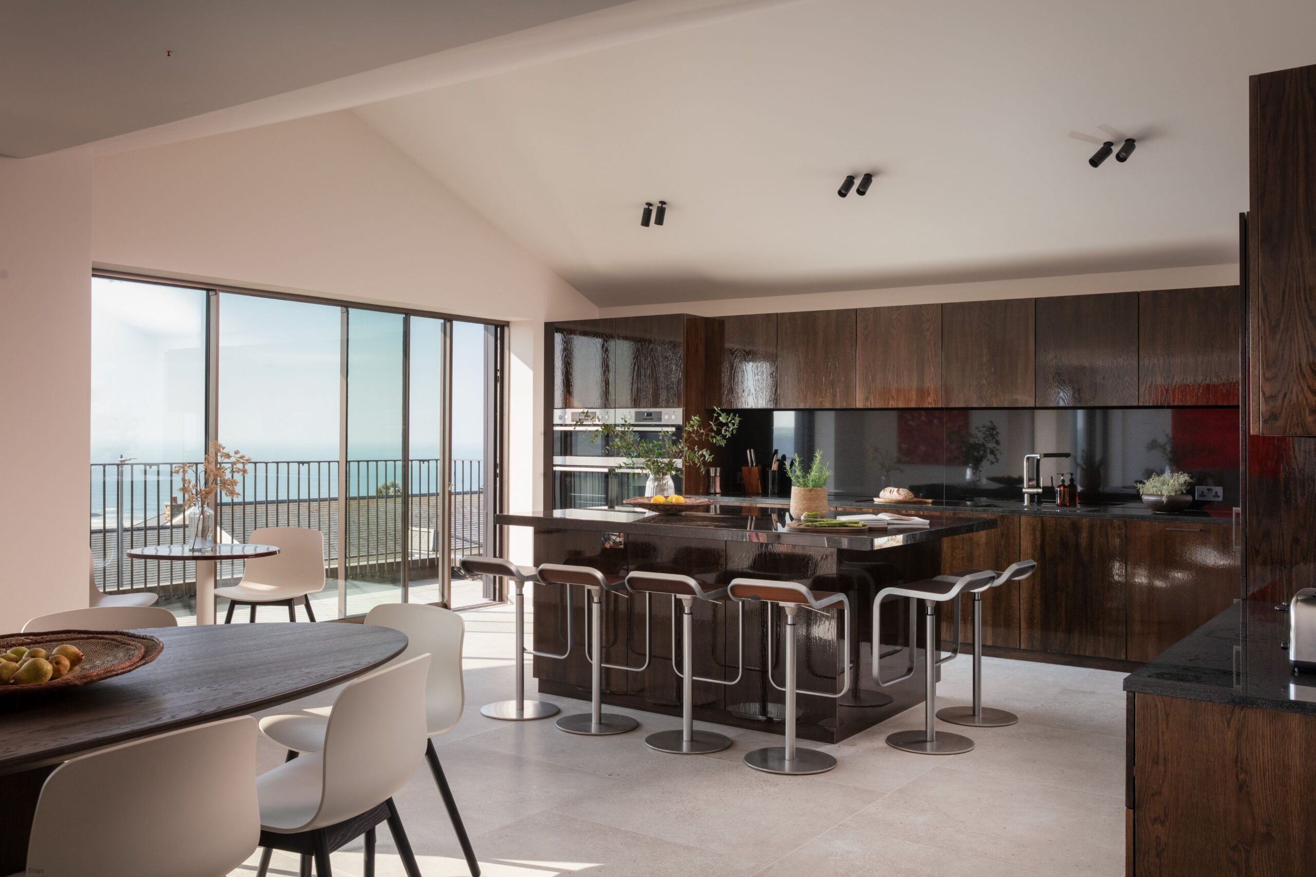 Modern kitchen with sleek dark wood cabinets and an island with barstools.