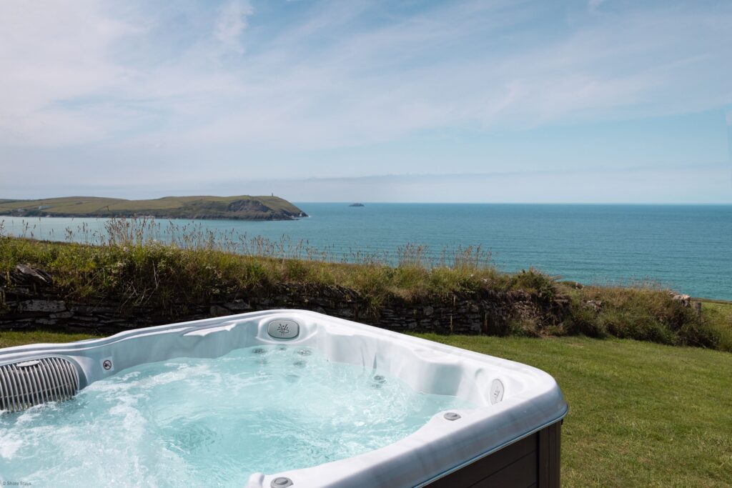 A hot tub on a grassy hill overlooking the sea.