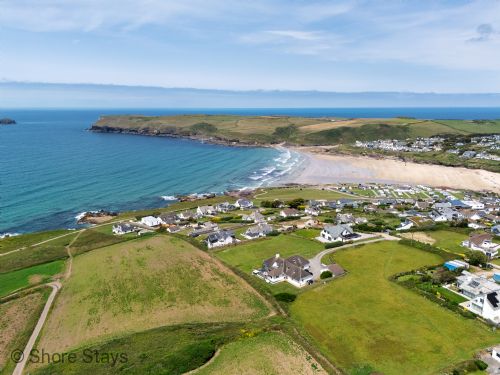 A coastal village with white houses and green fields.
