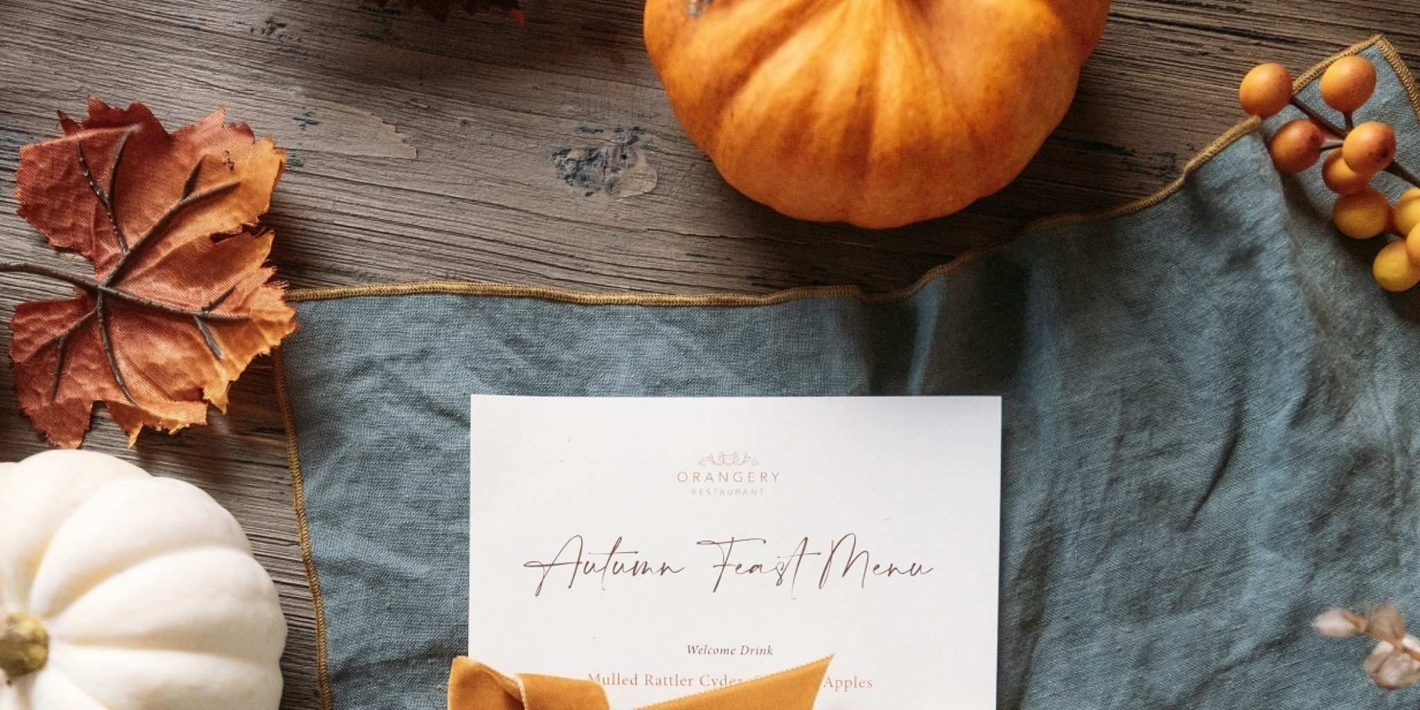 Autumn-themed table with pumpkins, autumn leaves, and berries around a menu