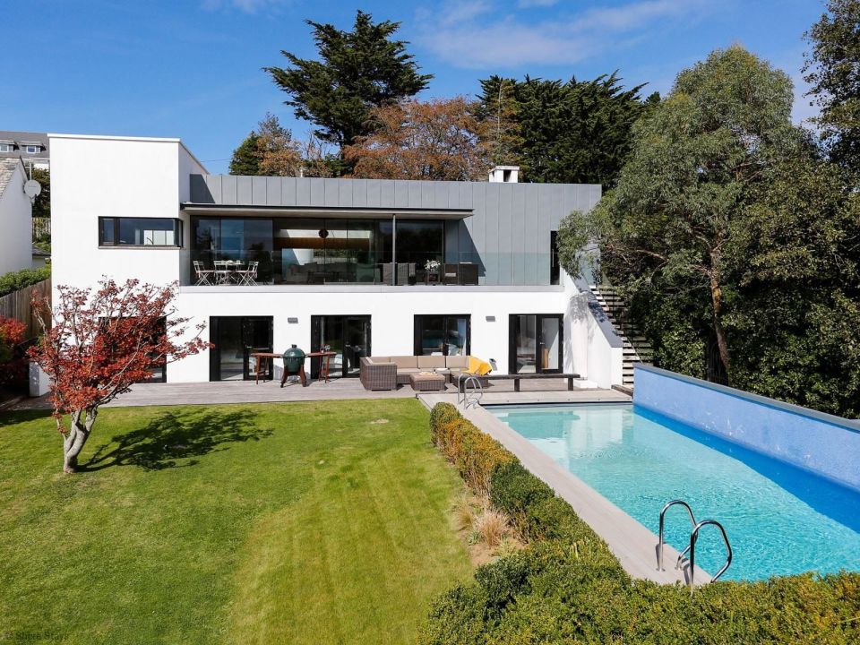 Modern two-story house with large windows and a long pool.