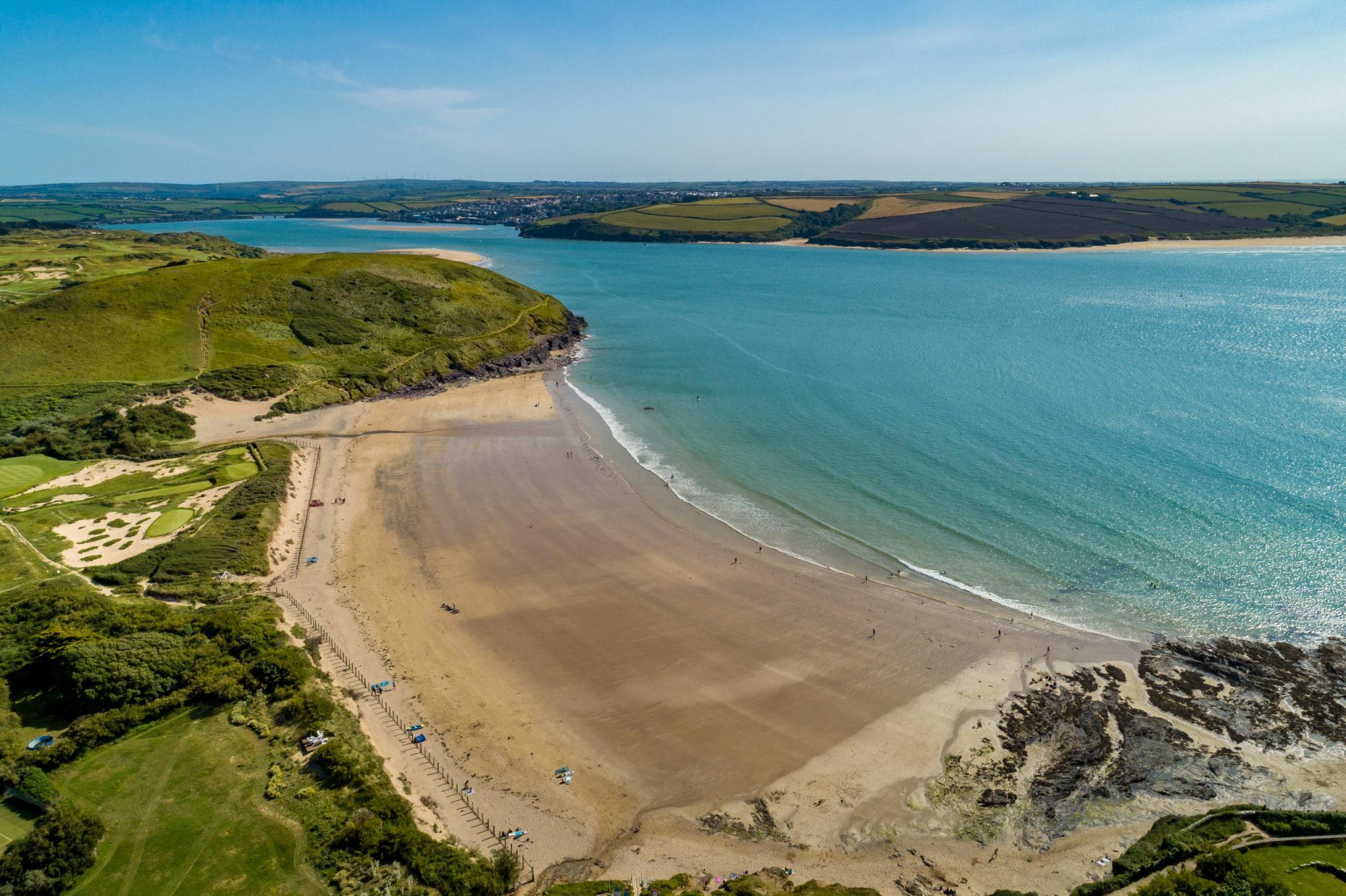 Aerial view of a beach with golden sand and waves meeting the shore