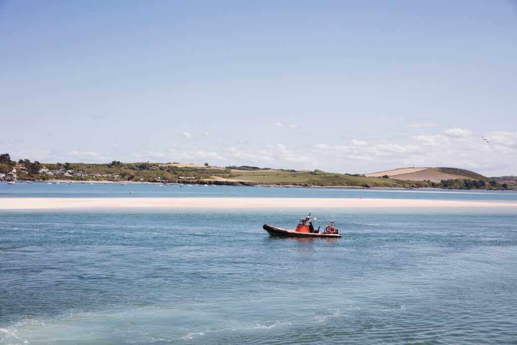 Panoramic view of an estuary with a small boat in the foreground.