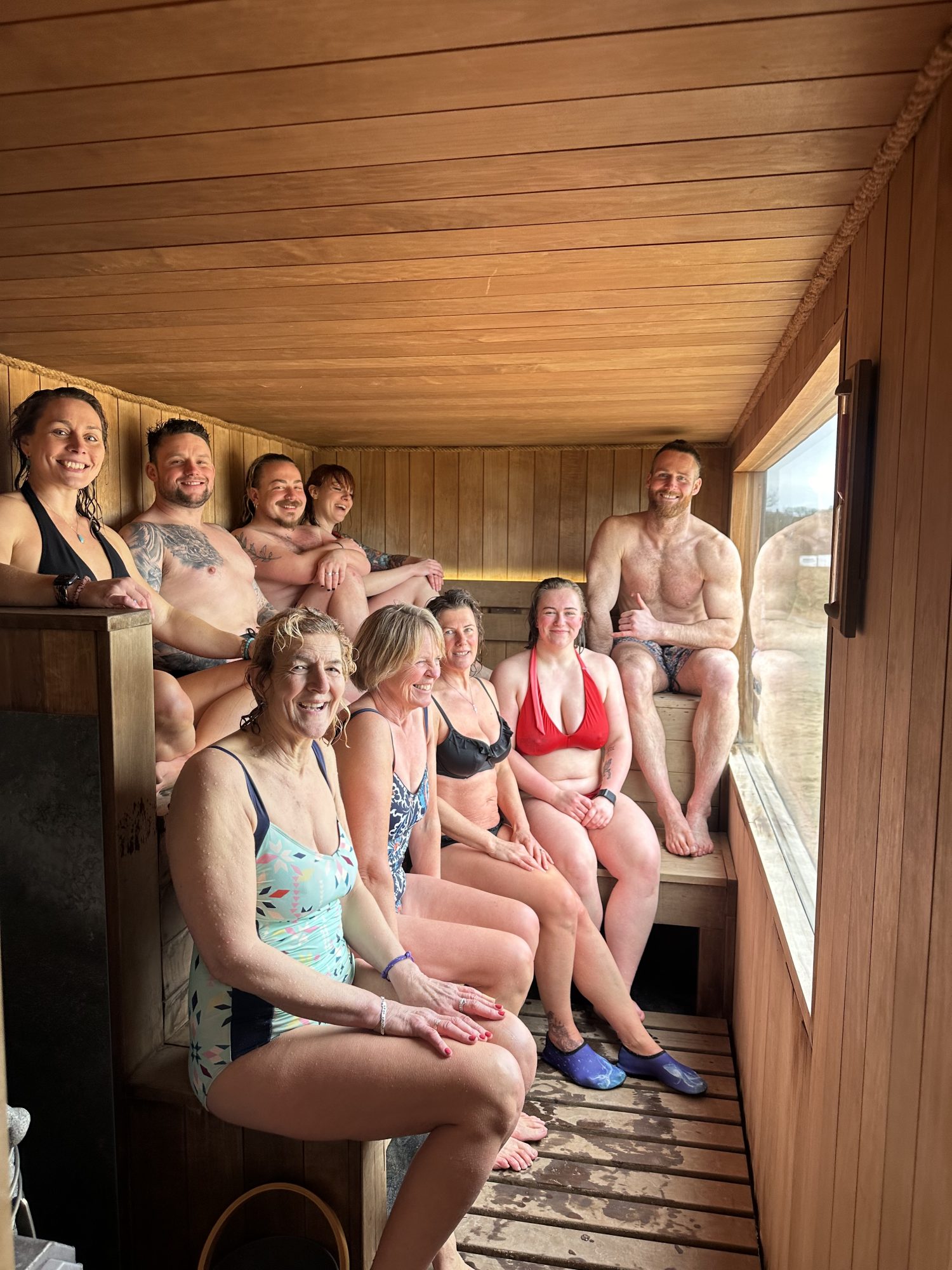 A group of people in swimsuits sitting inside a wooden sauna