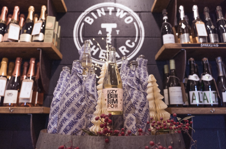 A wine shop display featuring a central bottle labelled "Fizzy Bum Bum" surrounded by wrapped bottles