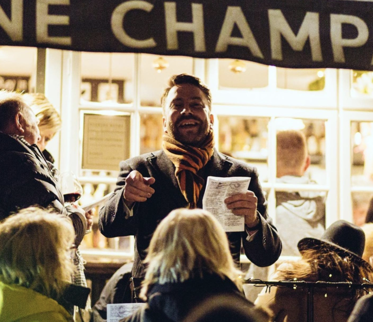 Man smiling and holding paper pointing at a crowd