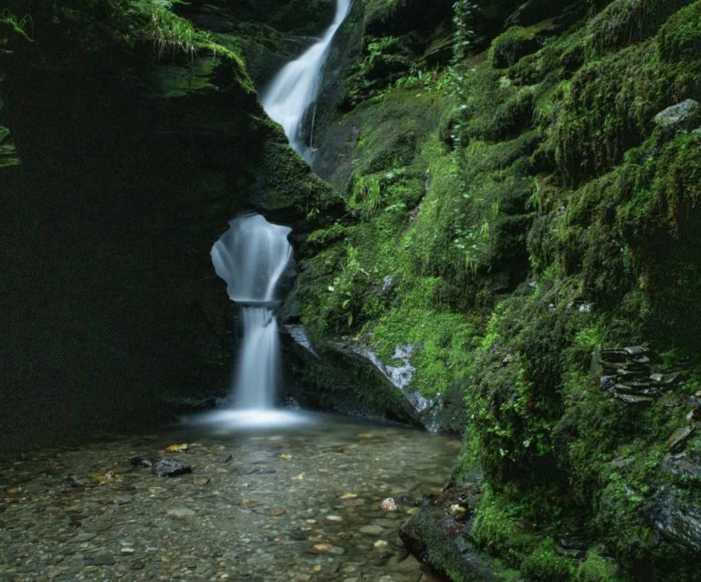 A waterfall cascading through rocks into a clear pool