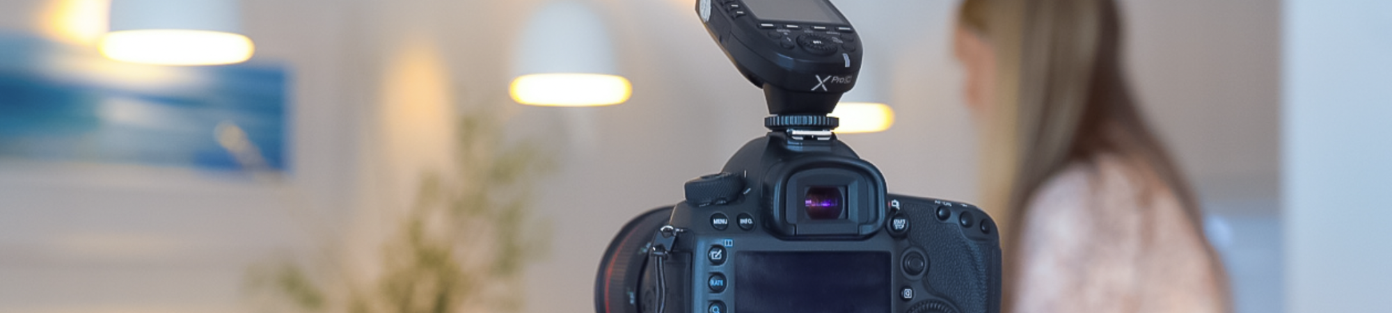 A DSLR camera with a flash attachment focused on a blurred scene showing a person in the background
