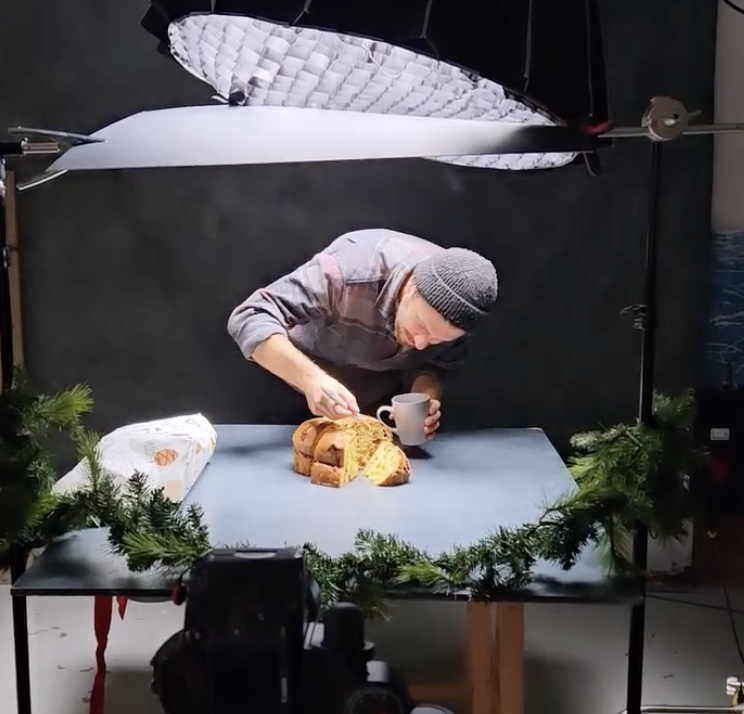 Man in a beanie carefully arranging panettone on a table