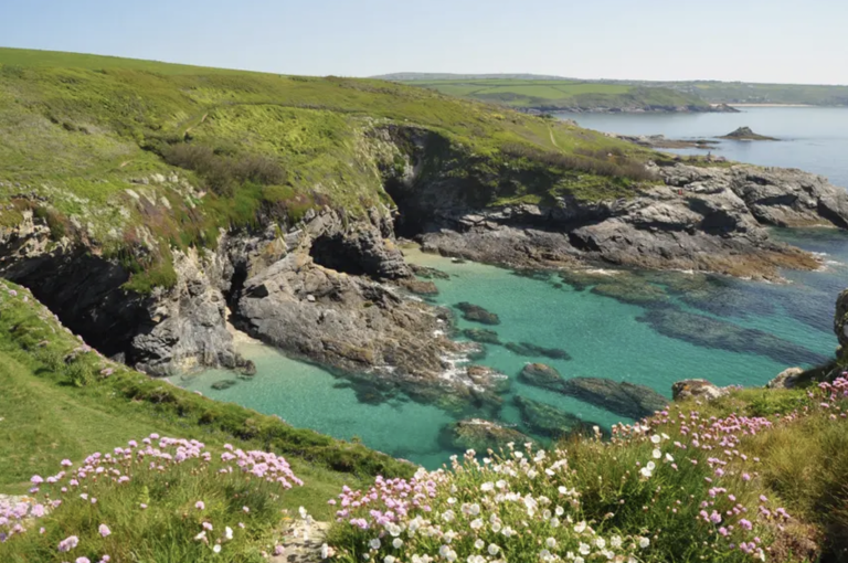 Coastal scene with turquoise water, rocky cliffs and green hills