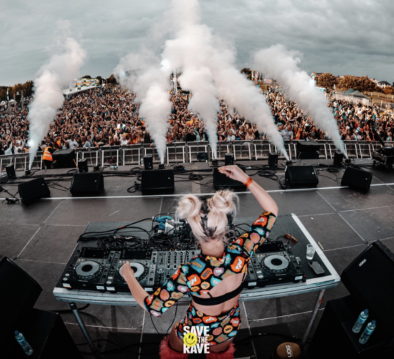 DJ performing on a large outdoor stage with an energetic crowd