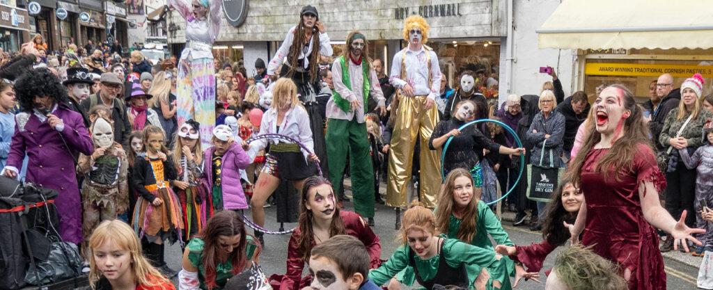 A street with festival-goers in colourful costumes and face paint