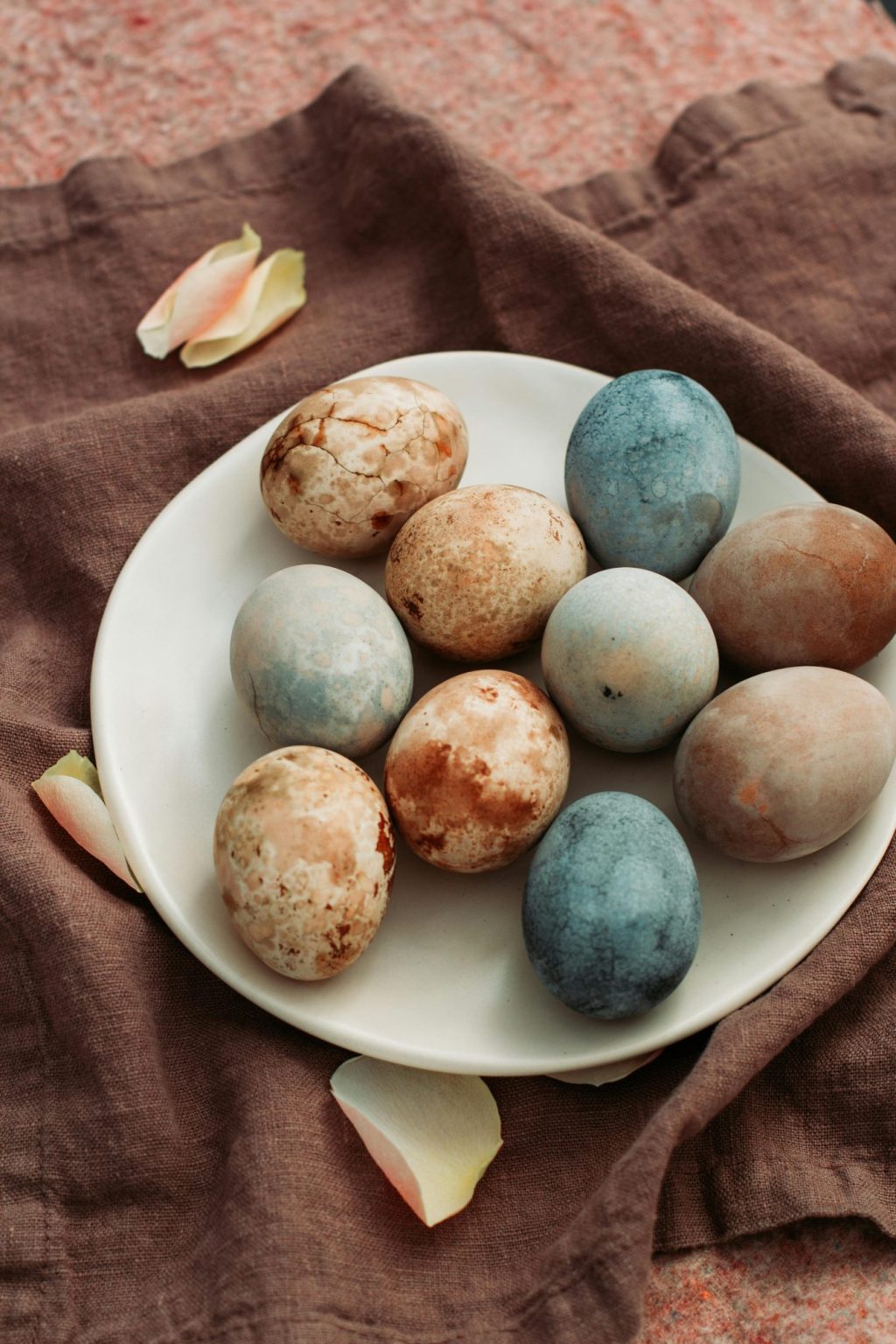 A white plate holding speckled, earth-toned Easter eggs